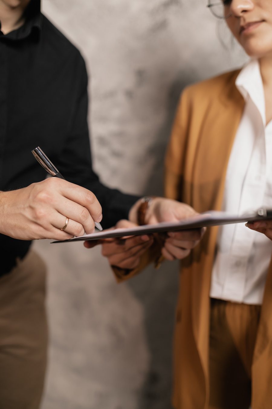 Two people reviewing and signing a document on a clipboard.
